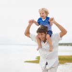 Father carrying boy on shoulders at beach